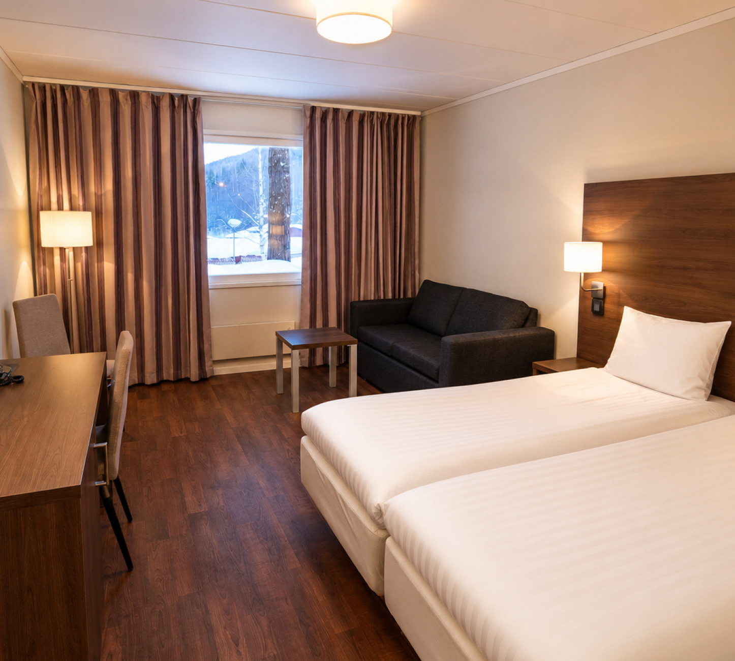 Lodge Hotel Clubrum på Hassela Ski Resort med två sängar, sittgrupp och skrivbord.